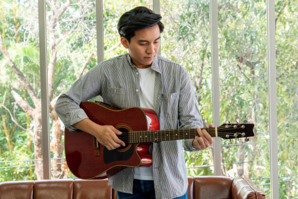 istock Young guitar player holding his guitar at home. 1222694804