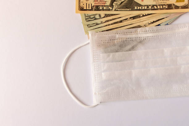istock CORONAVIRUS. Protective medical mask with American dollars. Close up. Selective focus. 1222694849