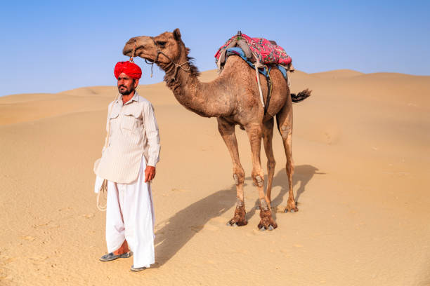 istock Indian man holding camel on sand dunes, Rajasthan, India 1222695242