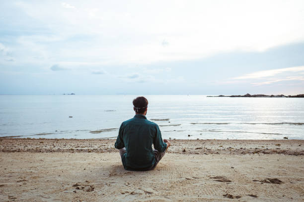 istock Young man meditating on the beach 1222695263