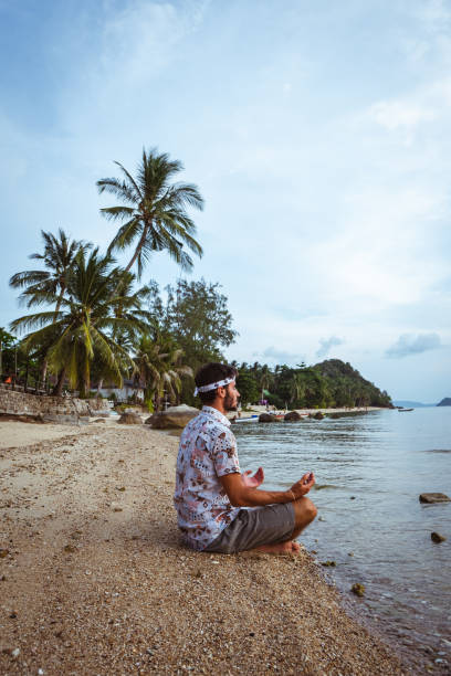 istock Young man meditating on the beach 1222695280