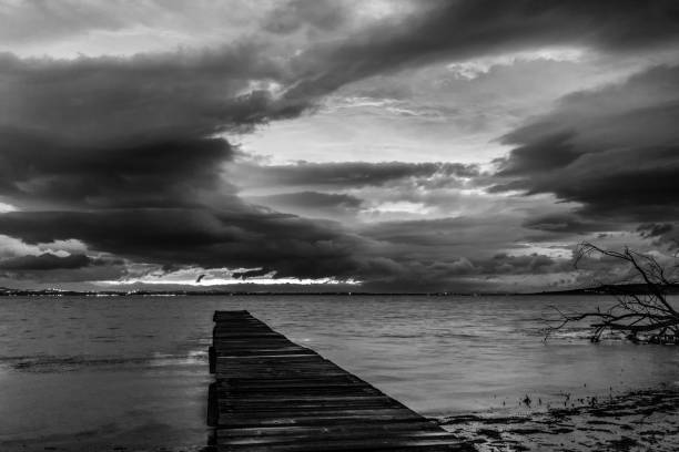 Black and white photo of the lighthouse on the pier of Norre Vorupor during storm and high waves, Jutland, Denmark.