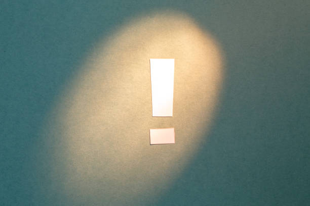 istock Exclamation mark cut out of paper on a textural green background highlighted by light 1222711956