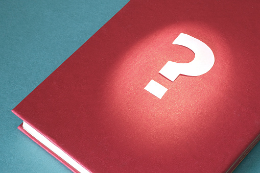 paper question mark made of paper on a red book. questions book