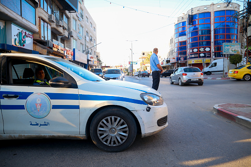 Police car close the street with a policeman officer on the road, West Bank, Palestinian Territories, Palestine - May 2, 2020