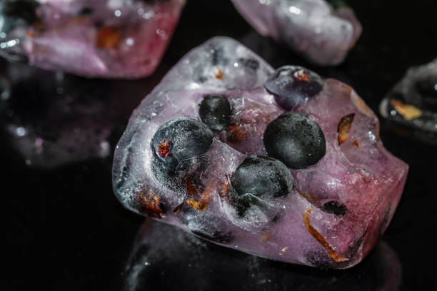 istock Black currant berries frozen in ice with reflection on dark background. Cracked ice. Closeup, selective focus 1222713250