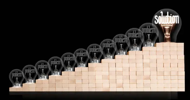 Group of shining and dimmed light bulbs on wooden block ladder with fibers in a shape of Problem and Solution concept words isolated on black background.