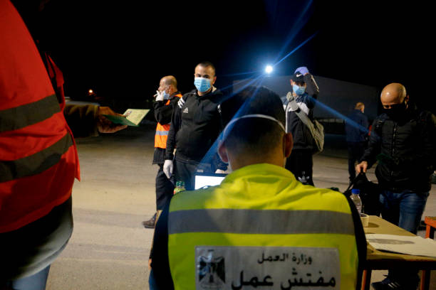 des travailleurs palestiniens masqués portent des effets personnels alors qu’ils se dirigent vers le travail en israel - ramallah historical palestine palestinian culture west bank photos et images de collection