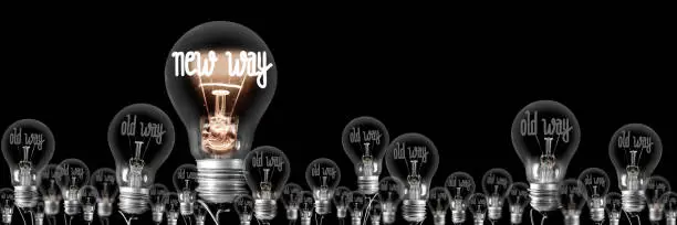 Large group of shining and dimmed light bulbs with fibers in a shape of New and Old Way words isolated on black background. Concept of Innovation, Development and Success