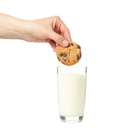 Woman dips cookies in a glass of milk, isolated on white background