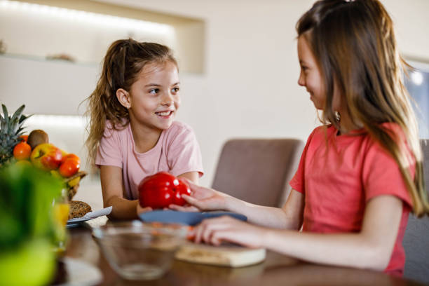 istock Happy sisters talking while preparing healthy meal in dining room. 1222717436