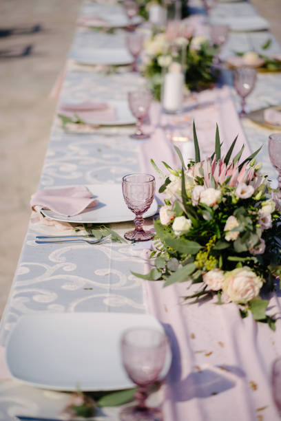 istock Close-up of a wedding dinner table. Table decoration in pink and white style - serving with white plates with pink glasses, napkins and dining path. Flower arrangements and candles are used in decor 1222718564