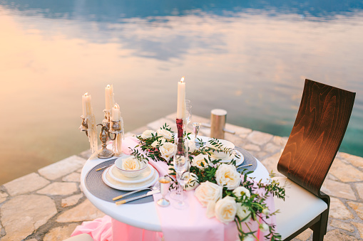 Close-up of a wedding dinner table at reception. Romantic sunset dinner on beach. A table by sea, at sunset. Dinner for two. Romantic date