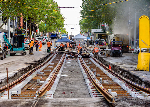 Melbourne, Victoria, Australia, May 3rd  2020: Many road workers in orange vests are working on replacing tram tracks on a busy inner city street.