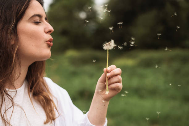 istock Young woman blowing a dandelion 1222723853
