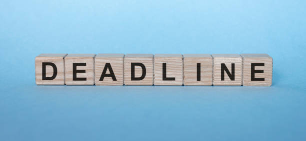 istock DEADLINE word written on wood block. DEADLINE text on blue background 1222725202