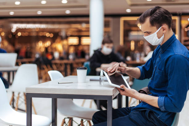istock man in protective mask wiping the screen of a digital tablet with antiseptic 1222730662