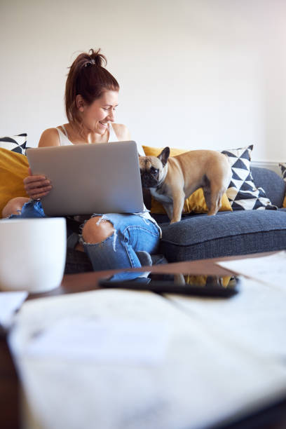 istock Female working on laptop with pet dog on sofa 1222731318
