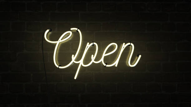 istock Bright neon yellow sign saying the word Open on a dark brick wall background, indicating a store, shop, pub or restaurant is now open for business sign. 1222734008