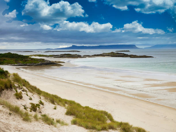 A view across Camusdarach Beach on the west coast of Scotland With the islands of Eigg and Rum on the horizon, a view across Camusdarach Beach on the west coast of Scotland - the beach featured  in the film Local Hero lochaber stock pictures, royalty-free photos & images