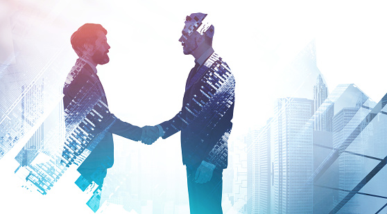 Silhouettes of two businessmen shaking hands in city. Concept of partnership and communication. Toned image double exposure