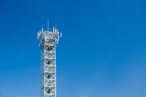 Telecommunication tower with antennas on blue sky. 4G and 5G cellular site base station. Wireless communication antenna transmitter.