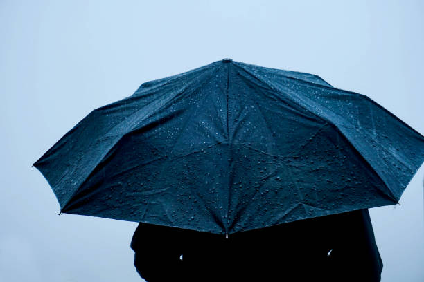 istock Alone man standing out in rain with an umbrella 1222740811