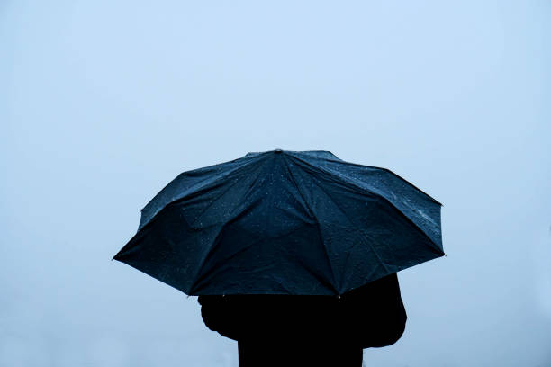 istock Alone man standing out in rain with an umbrella 1222740815
