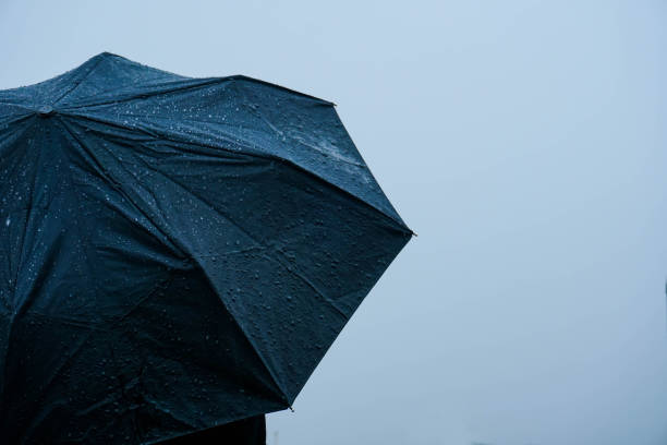 istock Alone man standing out in rain with an umbrella 1222740816