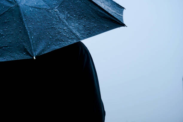 istock Alone man standing out in rain with an umbrella 1222740818
