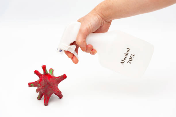 istock Hand spraying 70% alcohol on DIY homemade coronavirus model with modeling clay. Isolated on white background. 1222740839