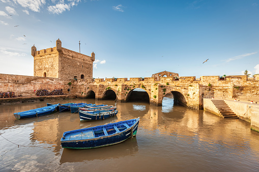 Blue wooden moroccan rowboats in the small fishing village harbor of Essaouira Port surrounded by old fortified Wall. Essaouira Port, Morocco, North Africa