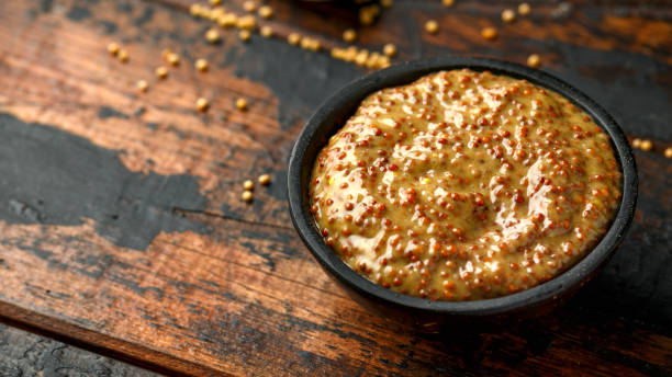 istock whole grain mustard in bowl on wooden table. 1222741057