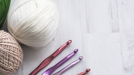 Balls of cotton and crochet needles on white background