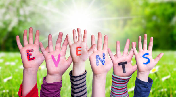 Children Hands Building Colorful Word Events. Green Grass Meadow As Background