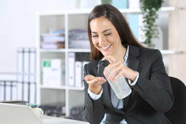 istock Happy executive using hand sanitizer in the office desk 1222745317