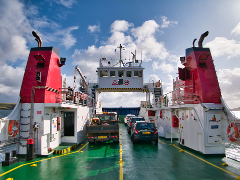 Between twin red funnels, vehicles on the car deck of the roll on/roll off car ferry from Laxo on Mainland to Symbister on Whalsay, taken on a sunny day with white clouds