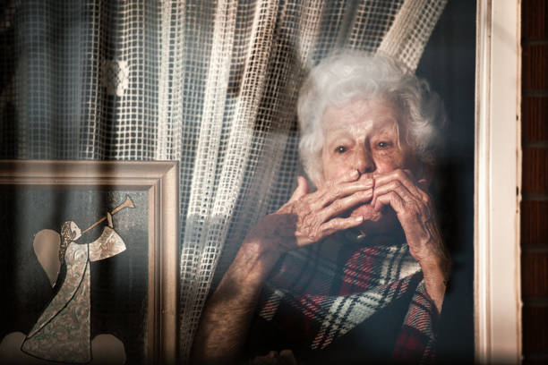 Catania, Sicily, Italy - April 17, 2013: Two women, one a senior, chat through an open window with lace curtains.