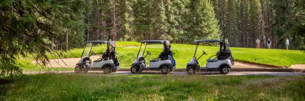 Photo of Row of empty electric carts on the side of the golf course, in Banff, Alberta, Canada