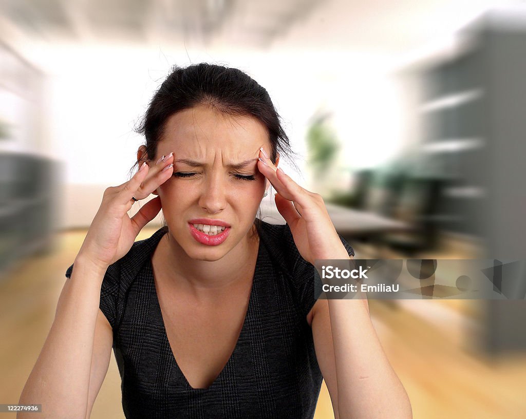 Woman heaving a headache Businesswoman heaving a headache at work Adult Stock Photo