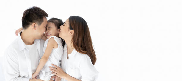 asiatische familie glücklich. vater, mutter küssen tochter, im alter von drei jahren und umarmen zusammen. auf dem weißen schwarzen boden. panorama-webbanner mit kopierbereich auf der rechten seite - kissing child family isolated stock-fotos und bilder