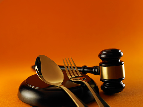 Wooden gavel spoon and fork over orange background usually use for law, and auction related concepts.