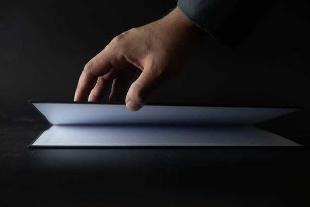 istock Businessman open empty page of paper on black background 1222756834