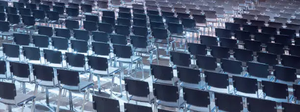 Photo of Empty seats. Equipped conference hall. Indoor business conference. Interior of a congress hall. Cancelled meetings, lectures, lessons, forums due to global disease. Online event. Web conference.