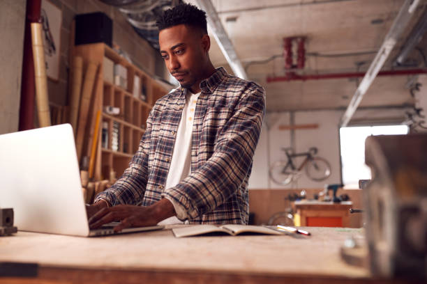 istock Male Craftsman In Carpentry Workshop For Bamboo Bicycles  Doing Accounts On Laptop 1222765039