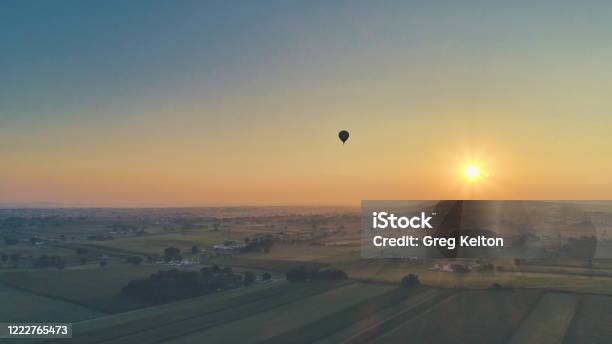 Aerial View Of A Summer Sunset Over Farm Lands With Blue Skies And Red Sun Stock Photo - Download Image Now