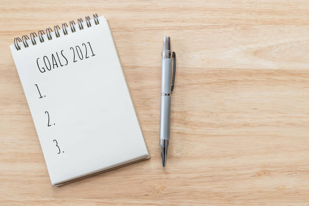 Top view of notepad with Goals List on wooden table, goals concept.