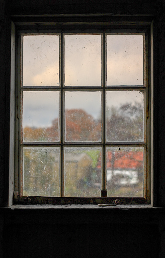 Looking out of a top floor window of a water mill looking on to a rural farm the window frame is silhouetted