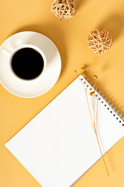 istock Top view sunny orange desktop with a blank notebook and a cup of coffee. 1222766679