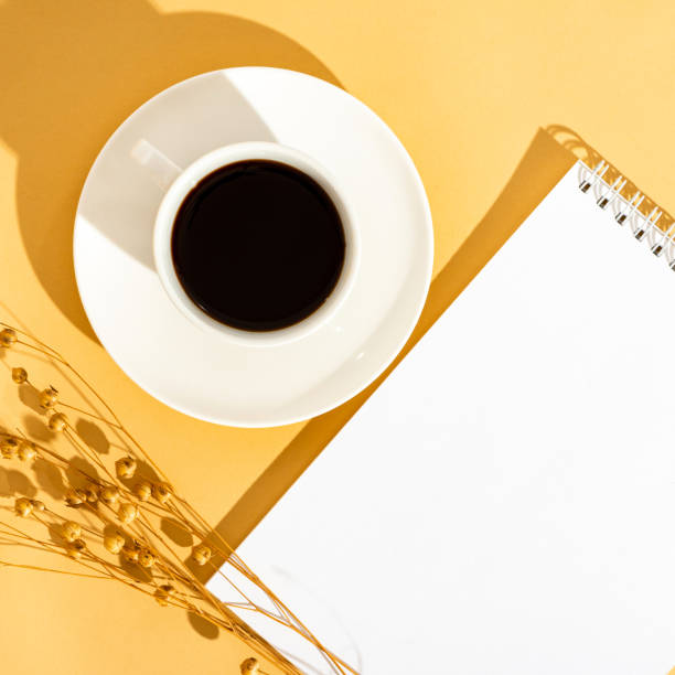 istock Top view sunny orange desktop with a blank notebook and a cup of coffee. 1222768503